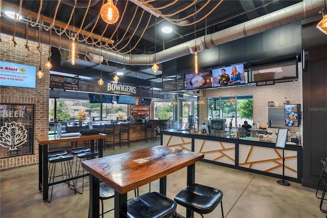 interior space featuring finished concrete flooring, brick wall, a high ceiling, and visible vents