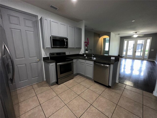 kitchen featuring ceiling fan, appliances with stainless steel finishes, light hardwood / wood-style floors, sink, and kitchen peninsula