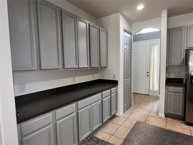 kitchen featuring stainless steel fridge, light tile patterned flooring, and gray cabinets