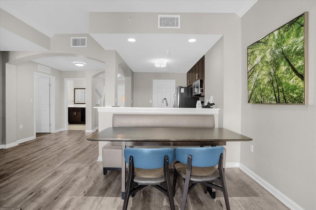 kitchen featuring stainless steel appliances, a peninsula, visible vents, and a kitchen breakfast bar