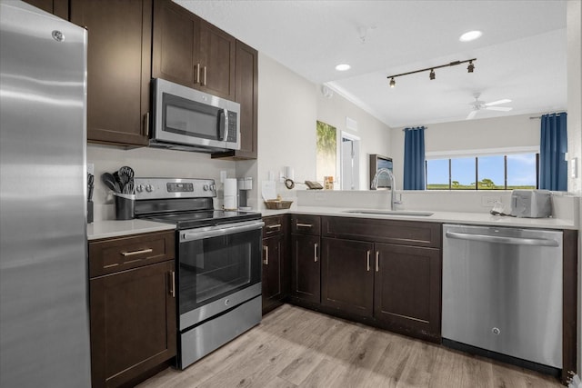 kitchen featuring appliances with stainless steel finishes, light countertops, dark brown cabinets, light wood-type flooring, and a sink