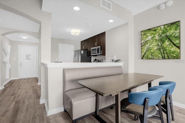 dining space with arched walkways, recessed lighting, visible vents, light wood-type flooring, and baseboards