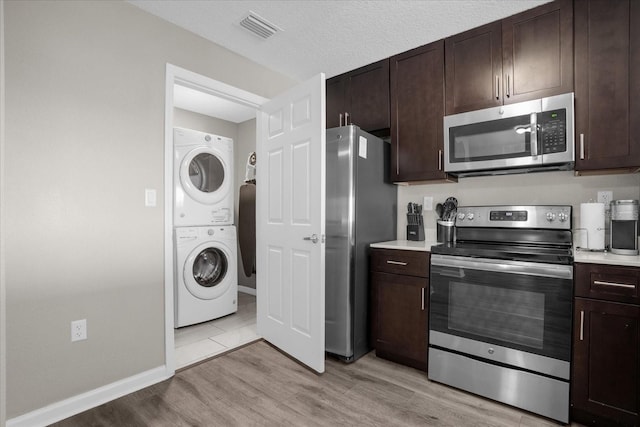 kitchen with visible vents, stacked washer and clothes dryer, stainless steel appliances, light countertops, and light wood-type flooring