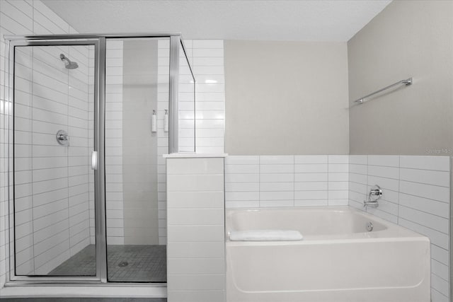 bathroom featuring a stall shower, a textured ceiling, and a bath