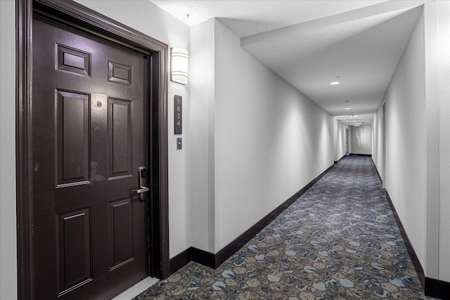 corridor with a textured ceiling and baseboards