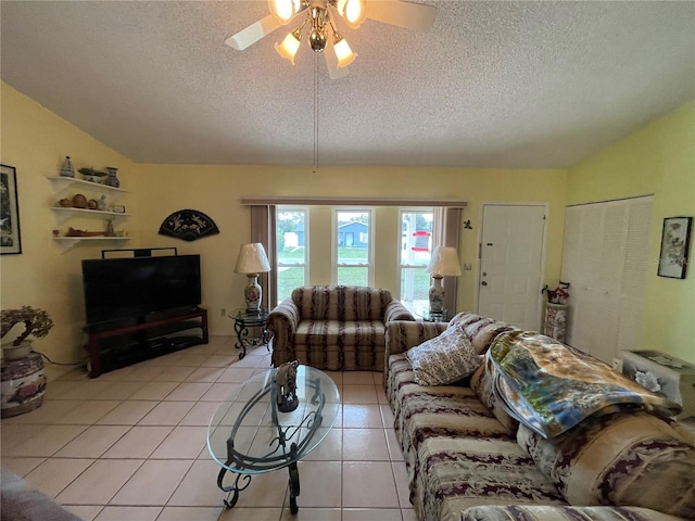 living room featuring ceiling fan, light tile patterned flooring, lofted ceiling, and a textured ceiling