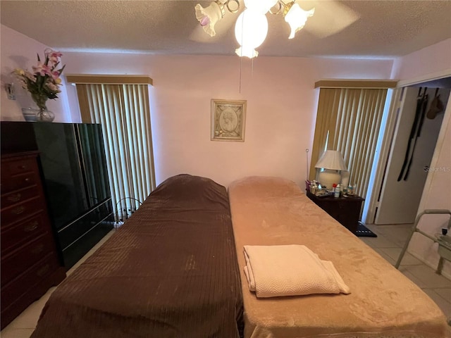 bedroom with tile patterned floors, ceiling fan, and a textured ceiling