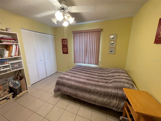 tiled bedroom with ceiling fan, a textured ceiling, and a closet