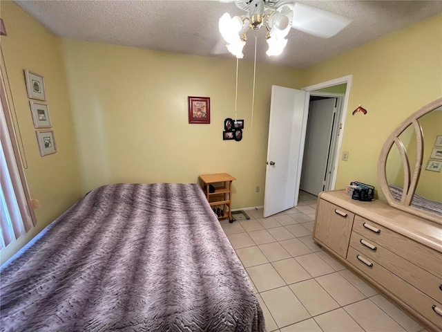 bedroom with ceiling fan, light tile patterned floors, and a textured ceiling