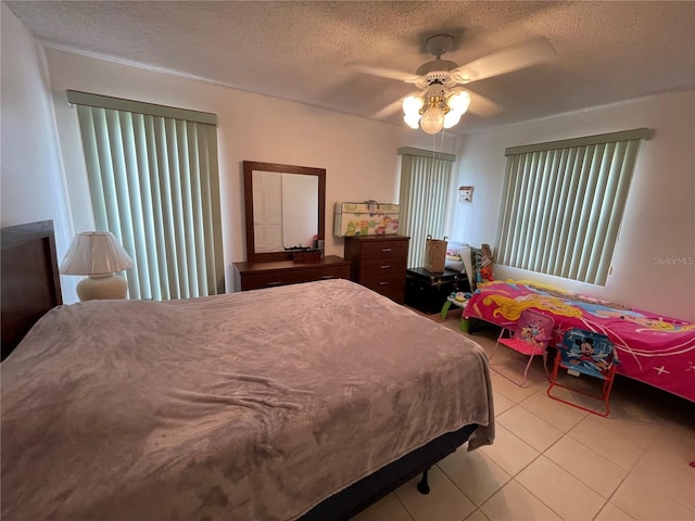 bedroom featuring ceiling fan, light tile patterned floors, and a textured ceiling