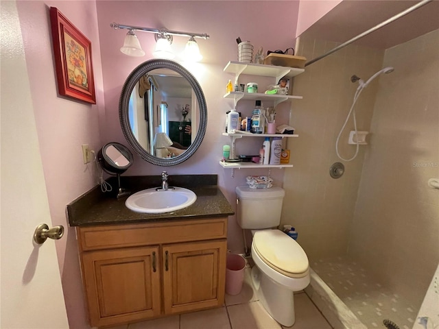 bathroom featuring toilet, a tile shower, vanity, and tile patterned floors