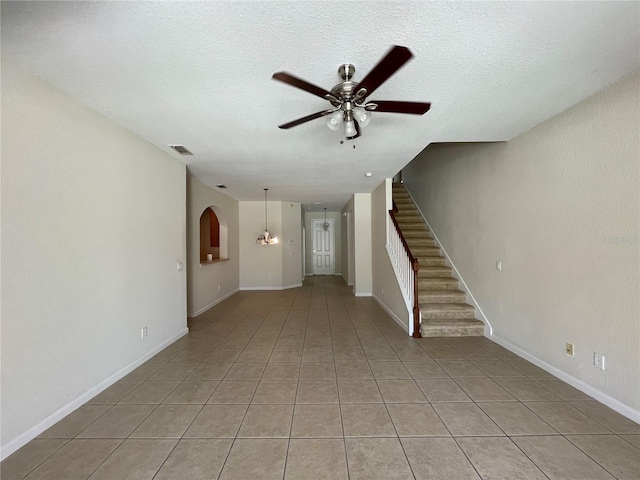 tiled empty room featuring ceiling fan and a textured ceiling