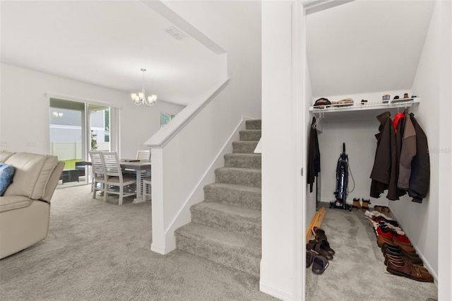 staircase featuring a chandelier and carpet floors