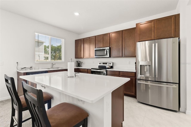 kitchen with light tile patterned floors, stainless steel appliances, a kitchen island, and sink