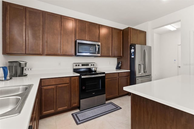 kitchen featuring light tile patterned floors, stainless steel appliances, and sink