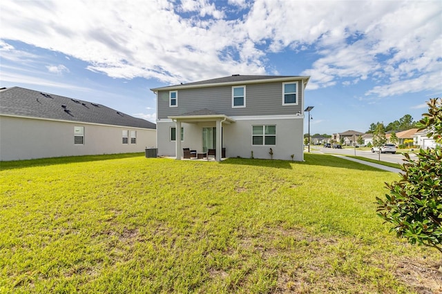 back of property with cooling unit, a lawn, and a patio area