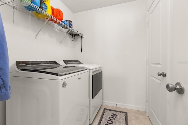 laundry room featuring washing machine and dryer and light tile patterned floors