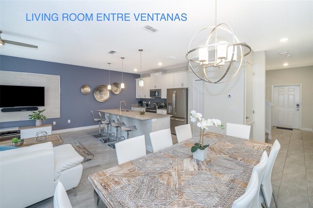 dining space featuring ceiling fan with notable chandelier, sink, and light tile patterned floors