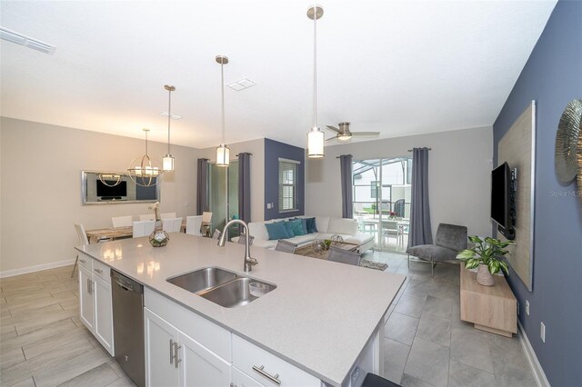 kitchen with ceiling fan with notable chandelier, sink, an island with sink, and dishwasher