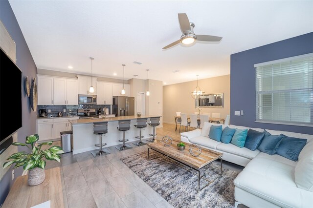 living room featuring ceiling fan with notable chandelier and sink