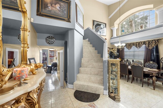 entryway featuring light tile patterned flooring, a high ceiling, and an inviting chandelier