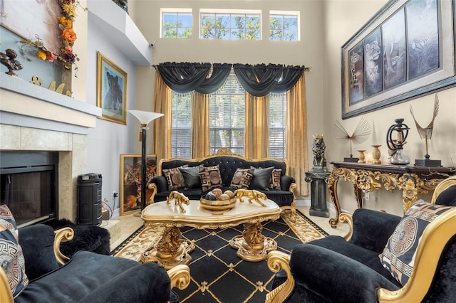 living room featuring a wealth of natural light, a tiled fireplace, tile patterned flooring, and a towering ceiling