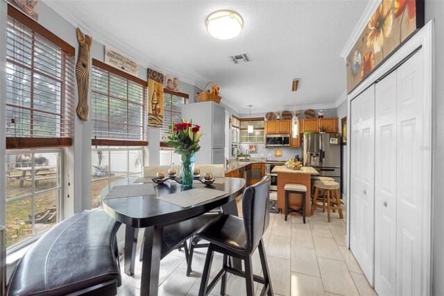 dining space featuring ornamental molding and light tile patterned floors