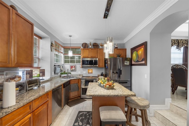 kitchen featuring light tile patterned flooring, ornamental molding, light stone counters, a breakfast bar area, and stainless steel appliances