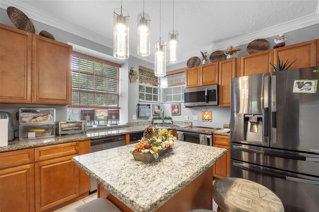 kitchen featuring a breakfast bar, a center island, ornamental molding, appliances with stainless steel finishes, and light stone countertops