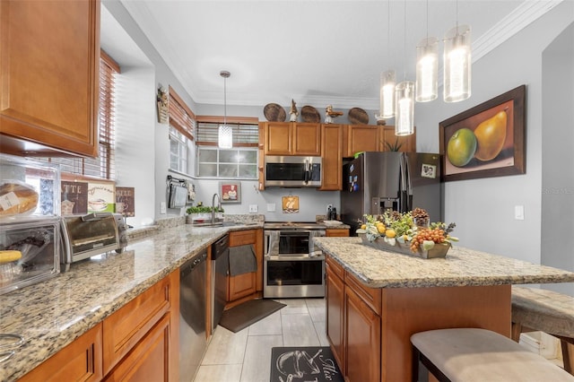 kitchen with appliances with stainless steel finishes, light stone counters, crown molding, pendant lighting, and a breakfast bar