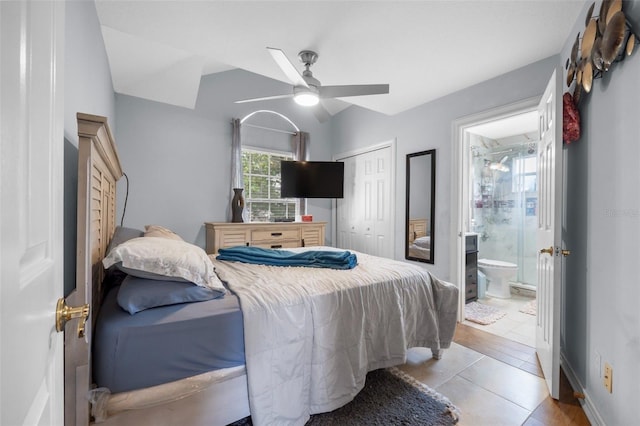 tiled bedroom featuring a closet, ceiling fan, ensuite bath, and lofted ceiling