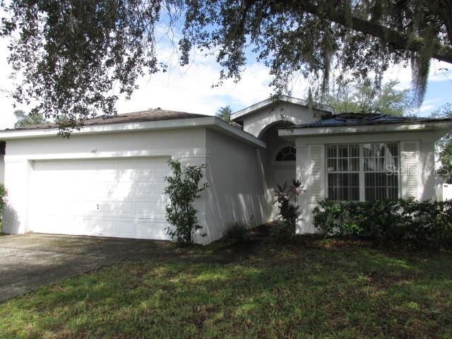 ranch-style house with an attached garage, driveway, a front lawn, and stucco siding