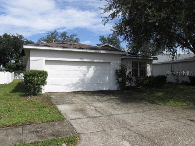 exterior space with concrete driveway, a lawn, an attached garage, and stucco siding