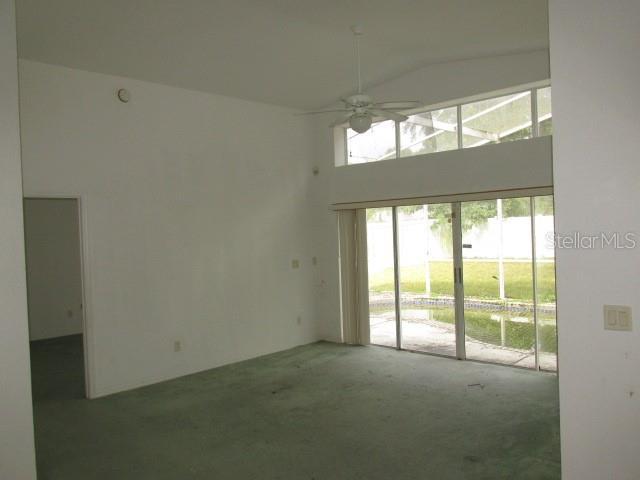 carpeted empty room featuring ceiling fan and a high ceiling