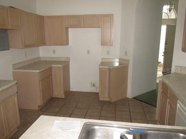 kitchen with light brown cabinetry, white dishwasher, and tile patterned floors