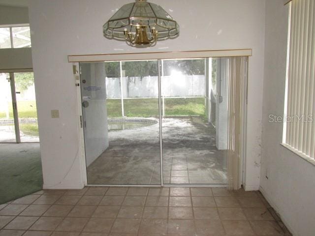 doorway to outside with light tile patterned floors, a chandelier, and light colored carpet