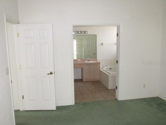 bathroom with a relaxing tiled tub, tile patterned flooring, and vanity