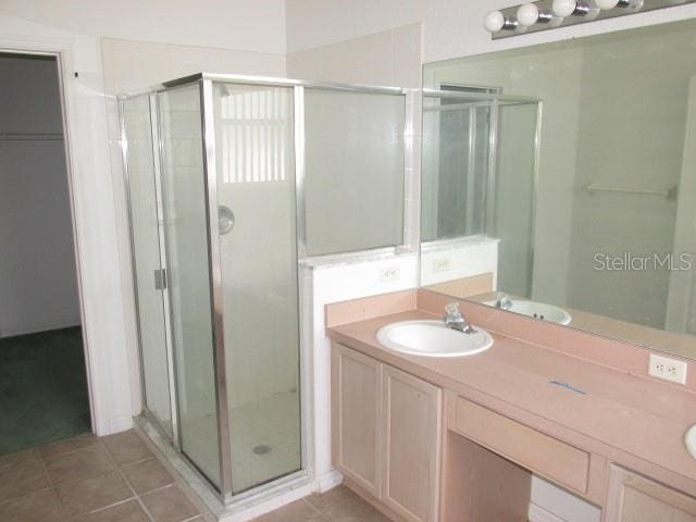 bathroom featuring tile patterned flooring, walk in shower, and vanity