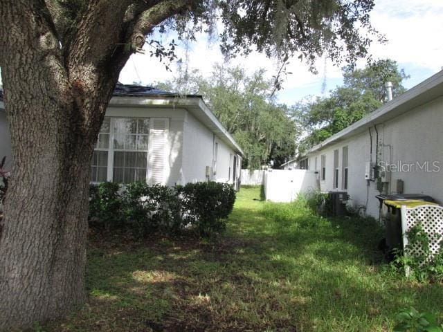 view of home's exterior featuring stucco siding, fence, and a yard