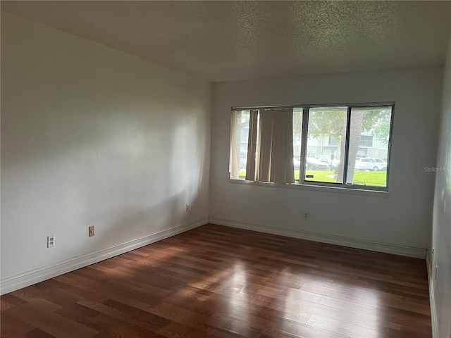 spare room featuring a textured ceiling and dark wood-type flooring