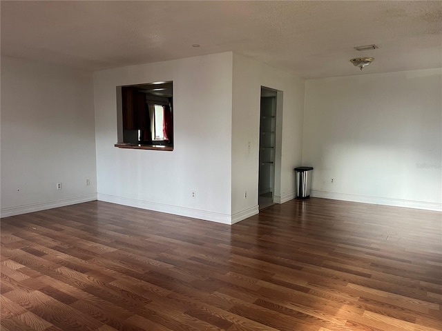 spare room with a textured ceiling and dark hardwood / wood-style floors