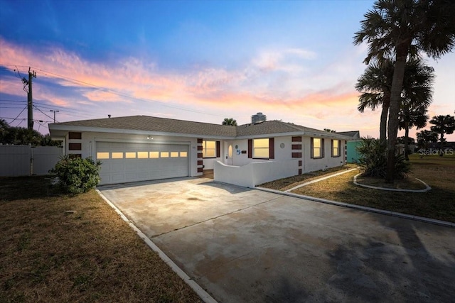 ranch-style home featuring driveway, stucco siding, an attached garage, fence, and a front yard