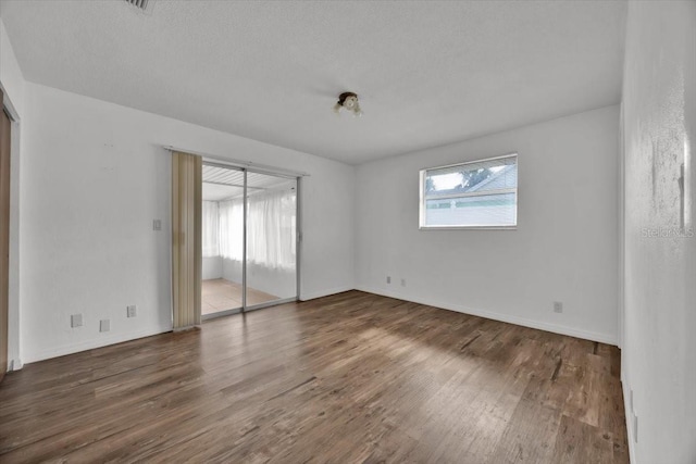 interior space featuring a textured ceiling, dark wood-style flooring, baseboards, and access to exterior