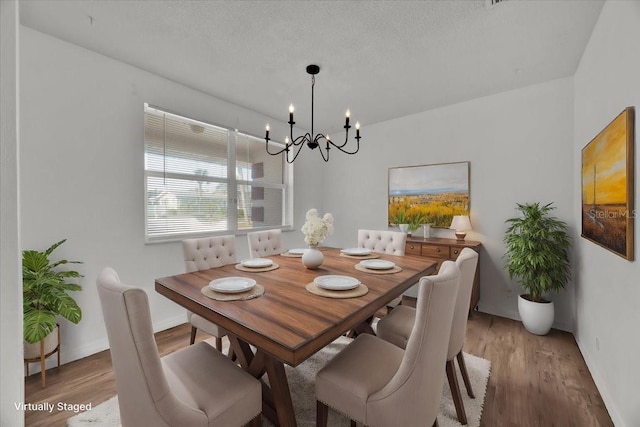 dining room with a textured ceiling, wood finished floors, and a notable chandelier