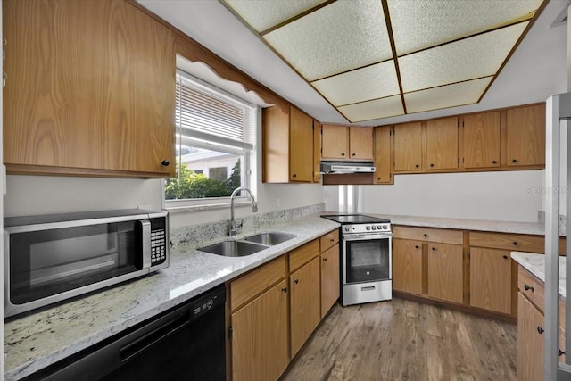 kitchen featuring brown cabinets, appliances with stainless steel finishes, a sink, light wood-type flooring, and under cabinet range hood