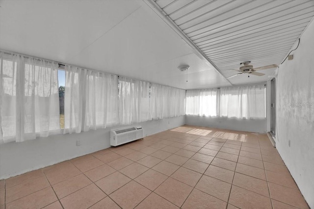 unfurnished sunroom with ceiling fan and a wall mounted AC