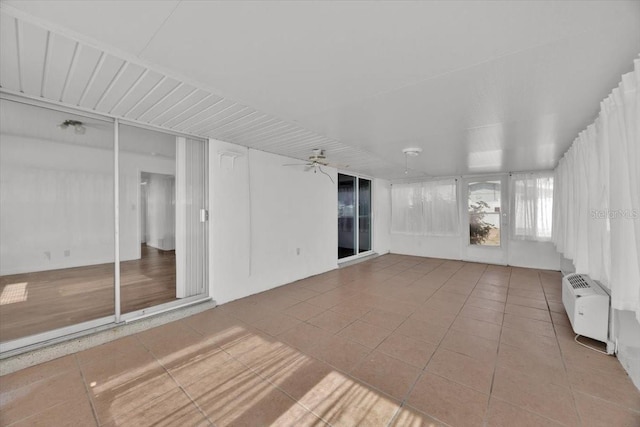 unfurnished sunroom featuring a wall unit AC and ceiling fan