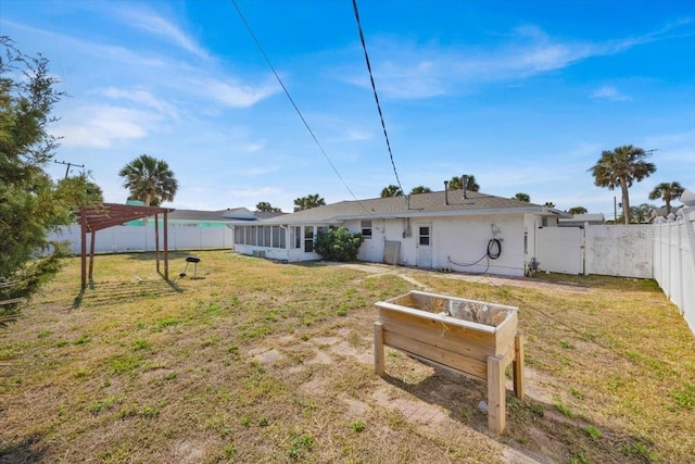 rear view of house featuring a sunroom, a fenced backyard, a yard, and a pergola