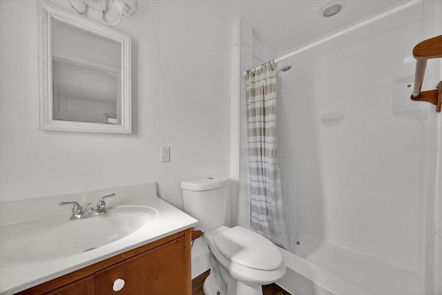 bathroom featuring toilet, a shower stall, and vanity