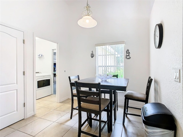 dining area featuring washer / clothes dryer, light tile patterned floors, and high vaulted ceiling